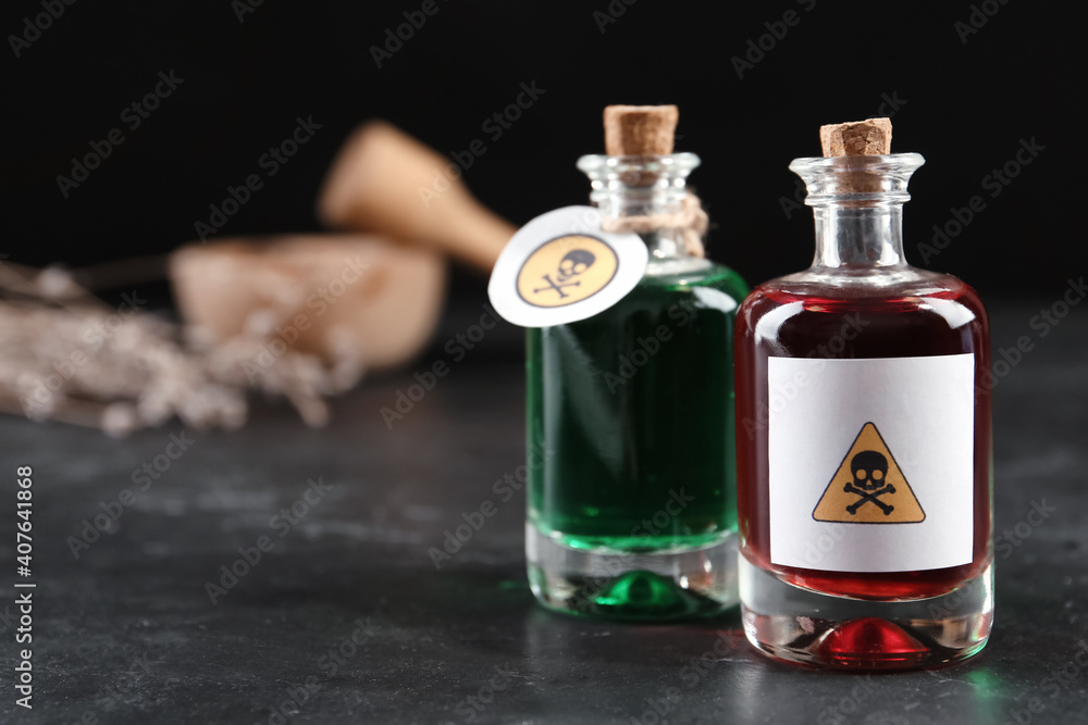 Glass bottles of poisons with warning signs on black table. Space for text Glass bottles of poisons with warning signs on black table. Space for text