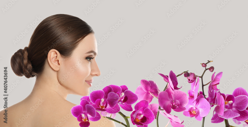 Beautiful young woman and orchid flowers on light background, banner design. Spa portrait Beautiful young woman and orchid flowers on light background, banner design. Spa portrait