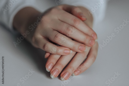 female hands. One hand rests on the other on a white background.