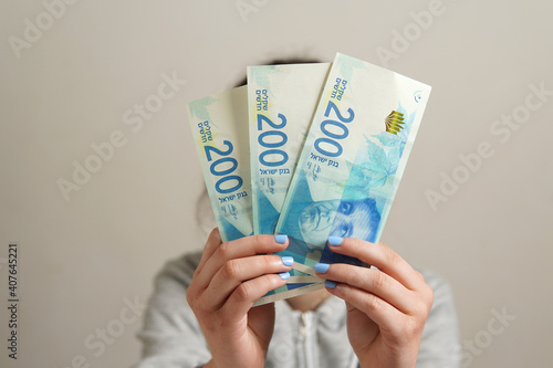 Foto Unrecognizable person holding three 200 Israeli Shekels banknotes - business, fi