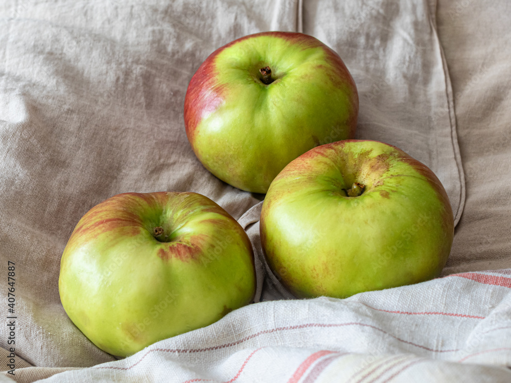 Three green apples lie on different fabrics Three green apples lie on different fabrics