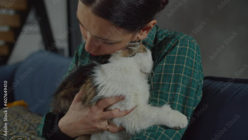 Affectionate caring attractive woman embracing, bonding with relaxed lovely adopted form animal shelter one eyed male cat, showing warm feelings, friendship and contentment while resting indoors. Affectionate caring attractive woman embracing, bonding with relaxed lovely adopted form animal shelter one eyed male cat, showing warm feelings, friendship and contentment while resting indoors.