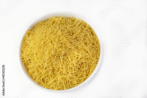 White bowl filled with dry and raw vermicelli on a white table photo