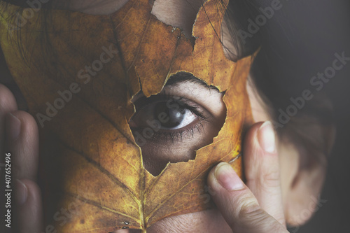 Photos woman hides her face with an autumn leaf, artistic and creative portrait