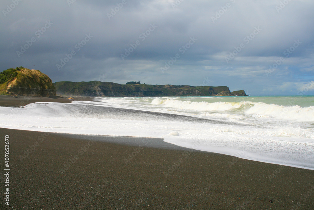 Whirinaki beach near Napier. Dark volcanic stone sand on a black sandy beach with huge Pacific Ocean waves, Hawke's Bay, Napier, North Island, New Zealand