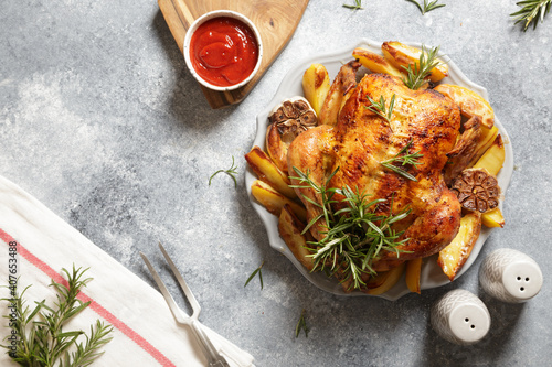 Photos baked whole chicken with rosemary, garlic and ketchup on gray concrete background