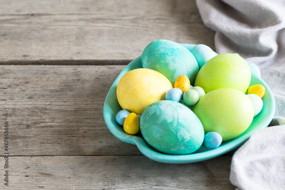 colorful easter eggs in a turquoise plate on a shabby wooden background colorful easter eggs in a turquoise plate on a shabby wooden background