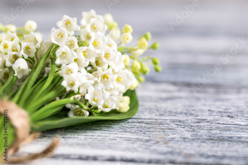 Obraz na plátně Bouquet of lilies of the valley on the blue wooden board