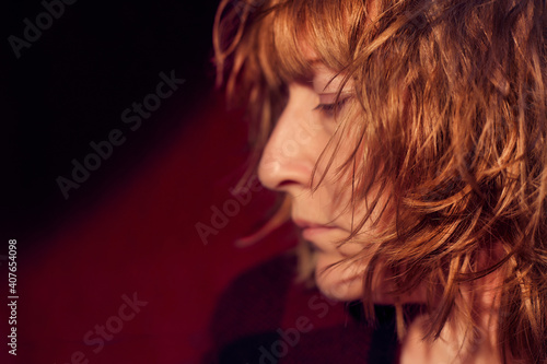 Portrait of tousled disheveled middle-aged woman on red background. Unprofessional female model in the Studio.