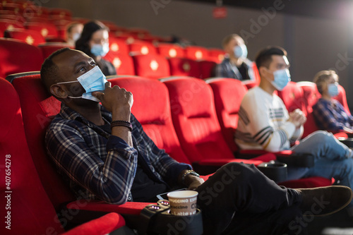 People sit in the cinema hall and watch a movie wearing medical masks and keep their distance. Covid-19 and the film industry
