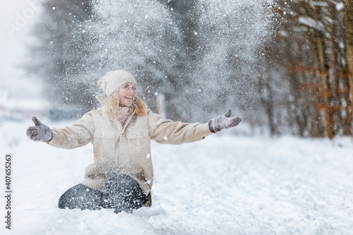 Winter playing woman throwing up snow in the park