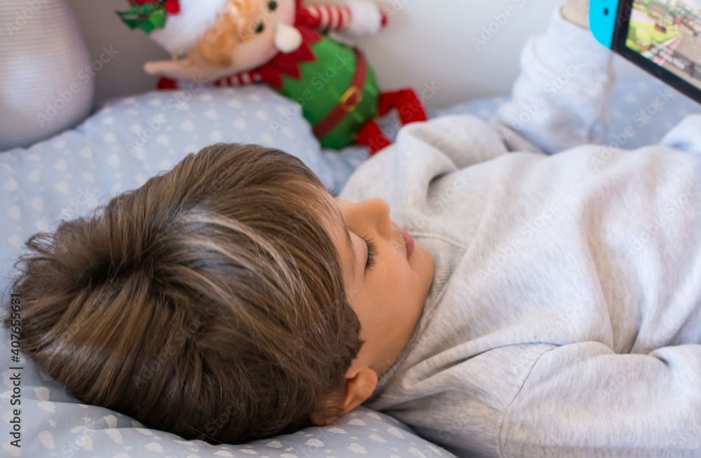 Boy Playing Video Games. A Boy Lying On His Bed Playing With His Tablet.Technology Boy Playing Video Games. A Boy Lying On His Bed Playing With His Tablet.Technology