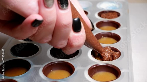 pouring the filling into the form of chocolates from a pastry bag