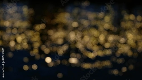 Abstract blurred Bokeh of golden light reflected in water surface at night time.Blur Festival lights flickering in river.