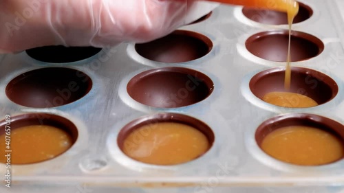 pouring the filling into the form of chocolates from a pastry bag