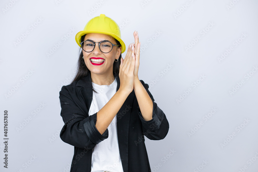 Young architect woman wearing hardhat clapping and applauding happy and joyful, smiling proud hands together
