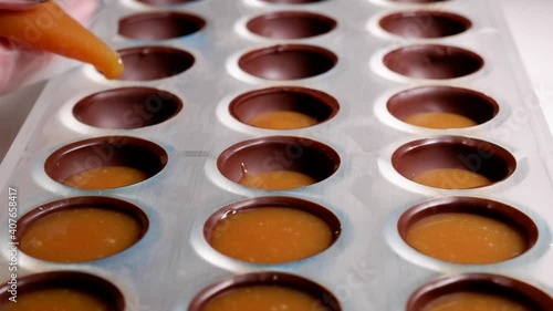 pouring the filling into the form of chocolates from a pastry bag