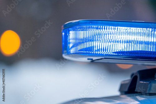 blue lights on the roof of a police car with the background out of focus and lights with bokeh effect