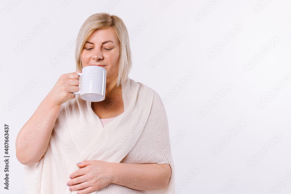 A blonde woman drinks aromatic tea on a white background with side space. A blonde woman drinks aromatic tea on a white background with side space.