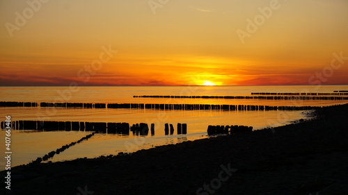 Sonnenuntergang an der Ostsee auf R  gen. Strahlende Oranget  ne mit Spiegelung im Wasser.