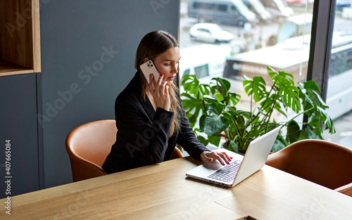 Business woman in home office working on laptop and talking on the phone photo