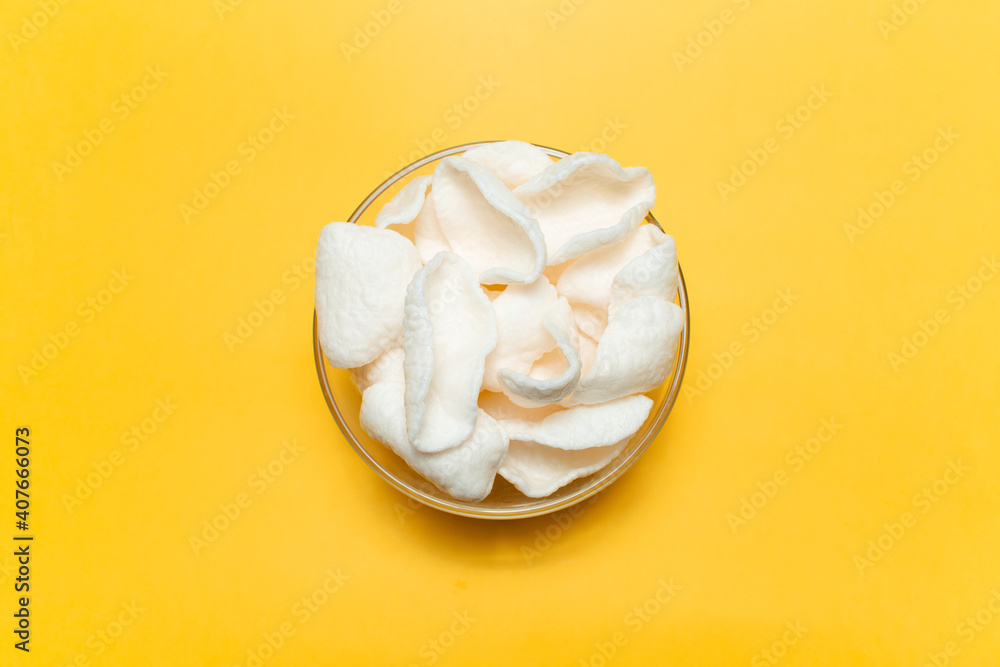 Top view of white chips in bowl on yellow background.