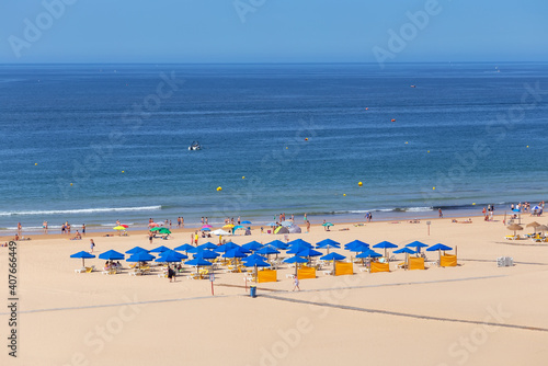 Nice clean aerial beach shot with lots of mainly blue umbrellas and a clear water and sky. © sergojpg