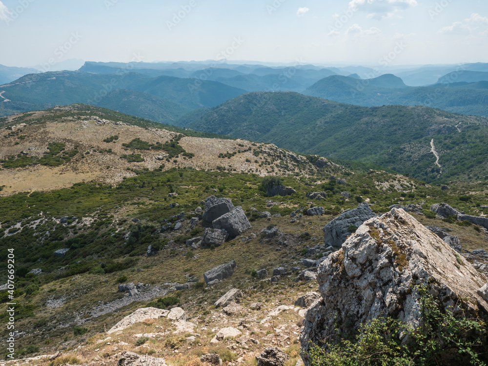 View from white limestone tower Perda Liana, impressive rock boulders, green forest hill and mountain. National Park of Barbagia, Central Sardinia, Italy, summer day