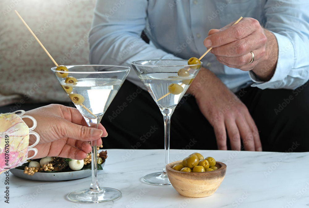 Fototapeta premium Young couple drinking martini cocktails together at home. Enjoy drinking after work during quarantine.