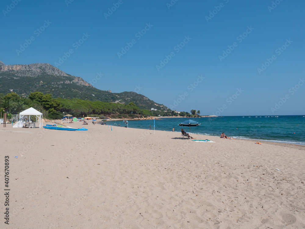 Santa Maria Navarrese, Sardinia, Italy, September 18, 2020: Sand beach Spiaggia di Santa Maria Navarrese with few sunbathing people and view of green hill of Monte Oro. Summer sunny day