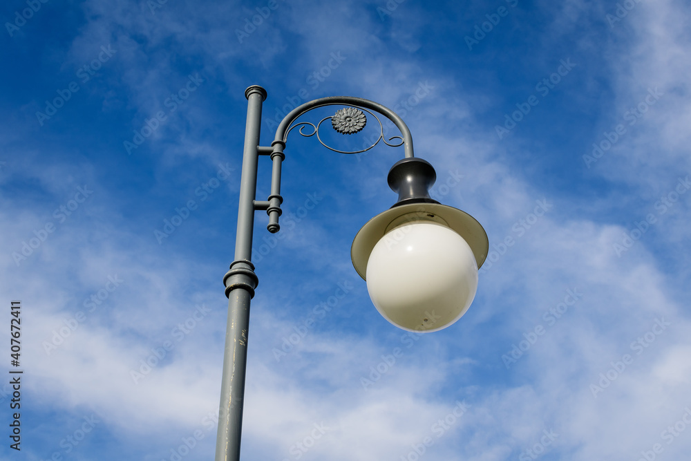 Modern lighting pole with cloudy blue sky in the background in a street in the old city center of Bucharest, Romania. Modern lighting pole with cloudy blue sky in the background in a street in the old city center of Bucharest, Romania.