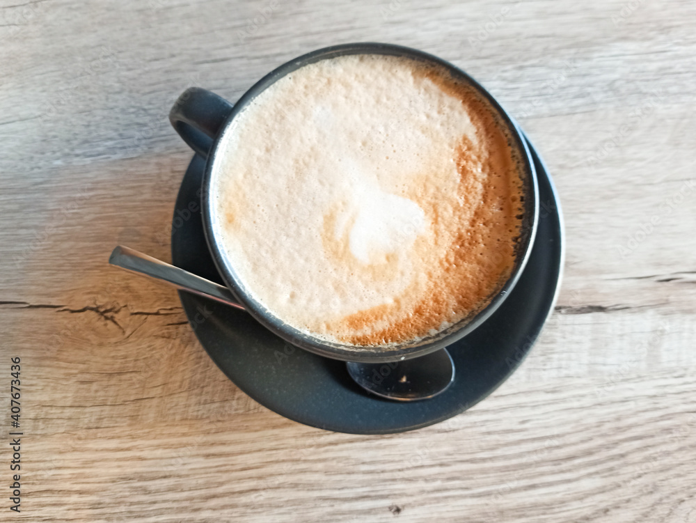 Close up cup of coffee with spoon on wooden background, cappuchino with shaked milk, view from the top, drinks topic Close up cup of coffee with spoon on wooden background, cappuchino with shaked milk, view from the top, drinks topic