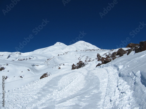 Mount Elbrus with two peaks against a blue sky on a bright sunny day, close-up