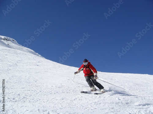 Woman skier going down to the hill alone and carving with no brand on her. Beautiful winter view. Mountains snowy day.