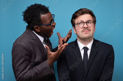 Angry mature businessman scolding his young employee for mistake, Studio shot.