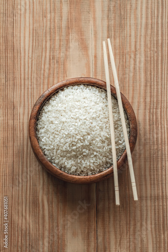 White rice in wooden bowl with wooden chopsticks