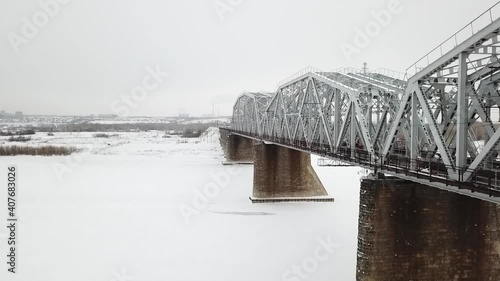 flying camera filming railway bridge over the river during winter