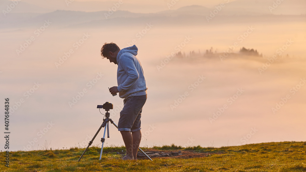 photographer watches the camera while shooting time lapse in the mountains
