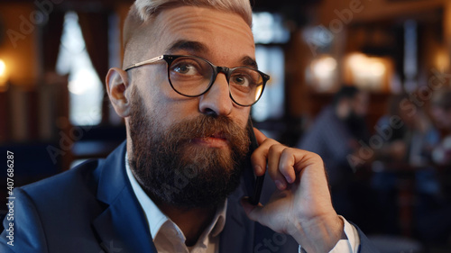 Close up of bearded businessman having phone call sitting in restaurant