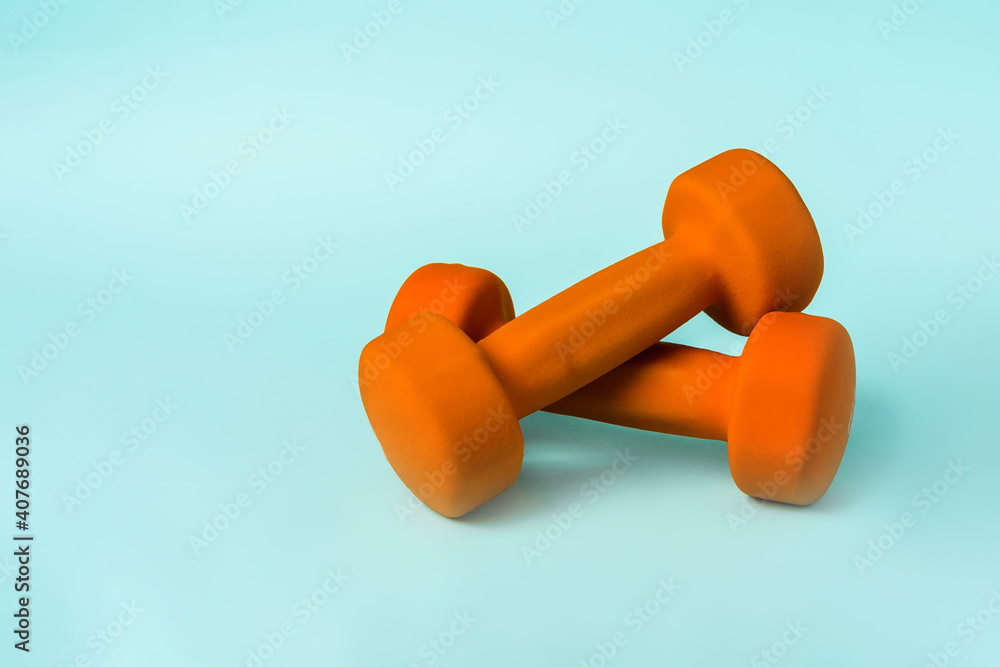 Orange dumbbells on a blue background, minimalist concept