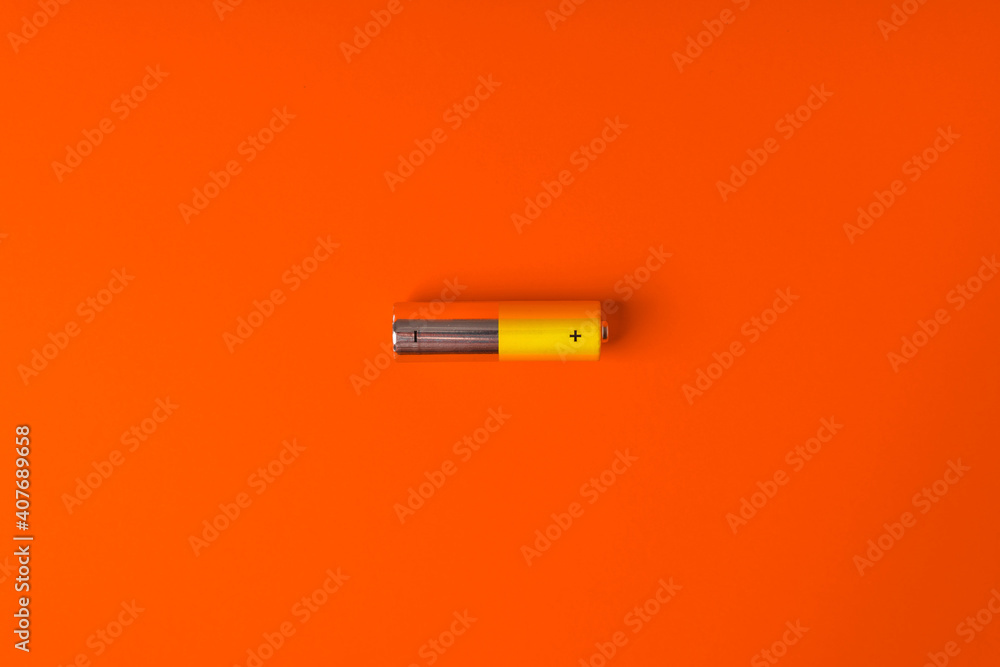 Yellow AA alkaline batteries on an orange background. Popular battery size. Copy the space. - obrazy, fototapety, plakaty 