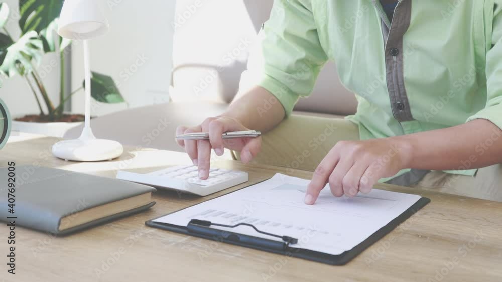 Young businessman calculating numbers from financial calculators and graphs in a private office, Dedicated to the progress and growth of the company, Financial and tax systems concept. Young businessman calculating numbers from financial calculators and graphs in a private office, Dedicated to the progress and growth of the company, Financial and tax systems concept.