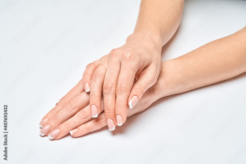 Beautiful Female Hands with French manicure over light grey background Beautiful Female Hands with French manicure over light grey background