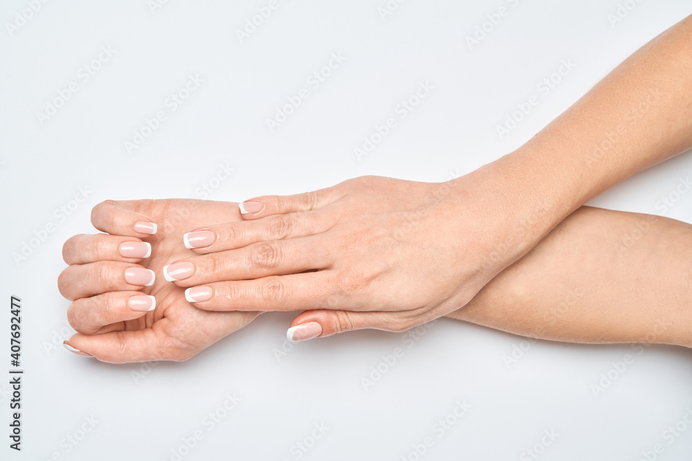 Beautiful Female Hands with French manicure over light grey background Beautiful Female Hands with French manicure over light grey background