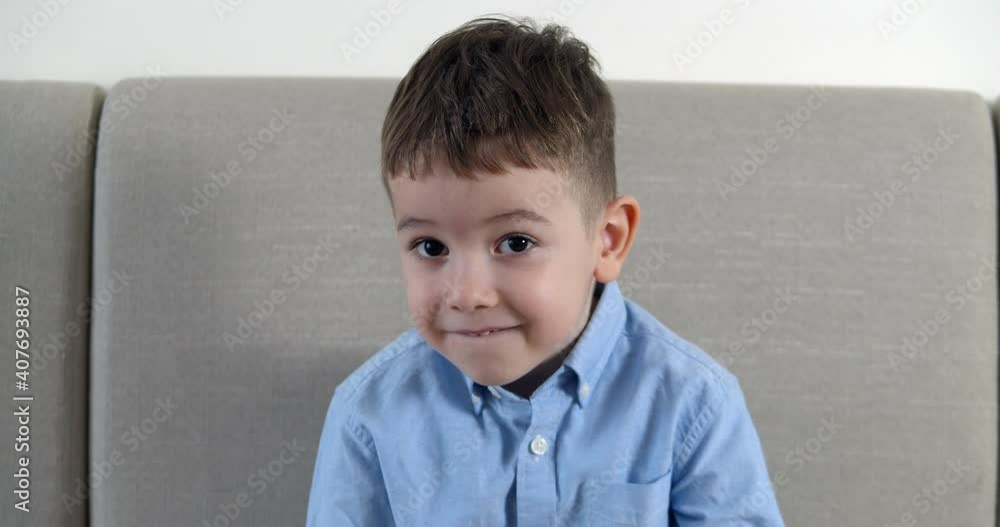 Portrait of funny little boy, smiling child, looking at camera, sitting on sofa at home, cute preschool child with joyful face, sitting on sofa. Happy childhood concept. Portrait of funny little boy, smiling child, looking at camera, sitting on sofa at home, cute preschool child with joyful face, sitting on sofa. Happy childhood concept.