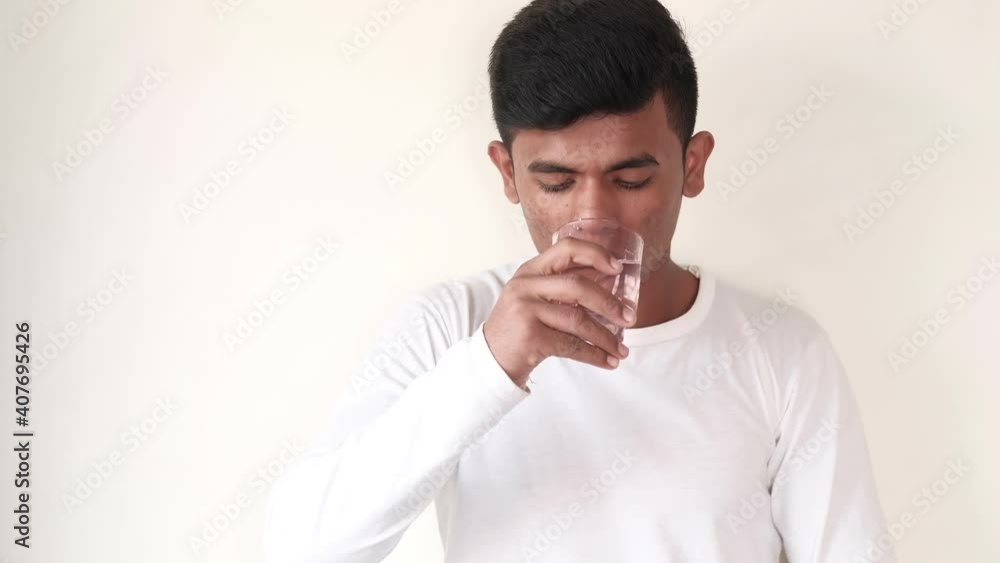 young man holding water glass and taking medicine young man holding water glass and taking medicine