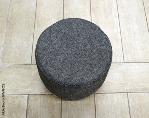 Top view of round fabric gray pouf. Wooden floor on  background