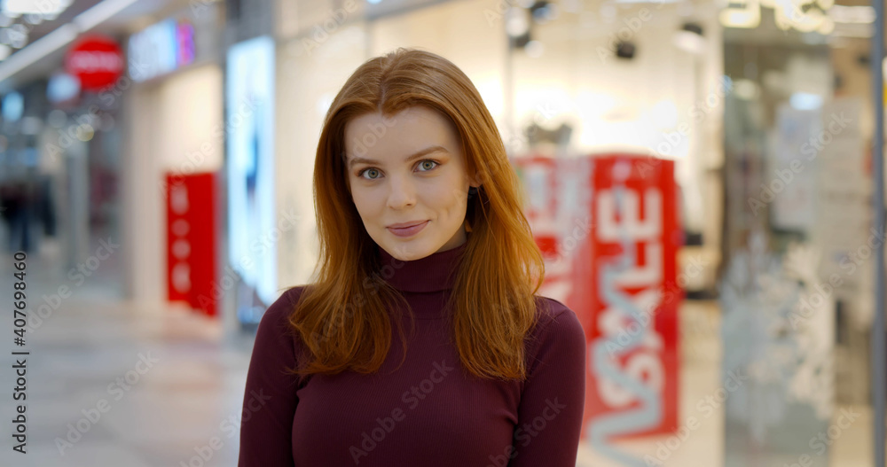 Portrait of happy young woman shopper standing in city mall