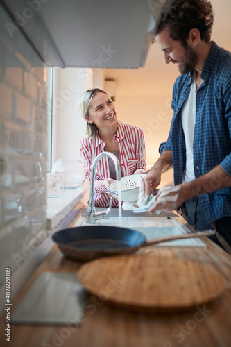 Obraz na plátně Cheerful couple doing the dishes together