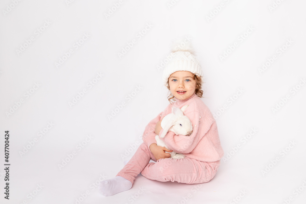a little girl in winter clothes holds a rabbit on a white background. New year's concept, space for text a little girl in winter clothes holds a rabbit on a white background. New year's concept, space for text